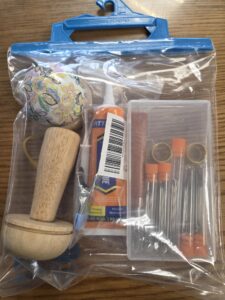 Image of plastic hanging bag containing 1 Wooden darning mushroom, 1 pin cushion, tube of needles, etc.