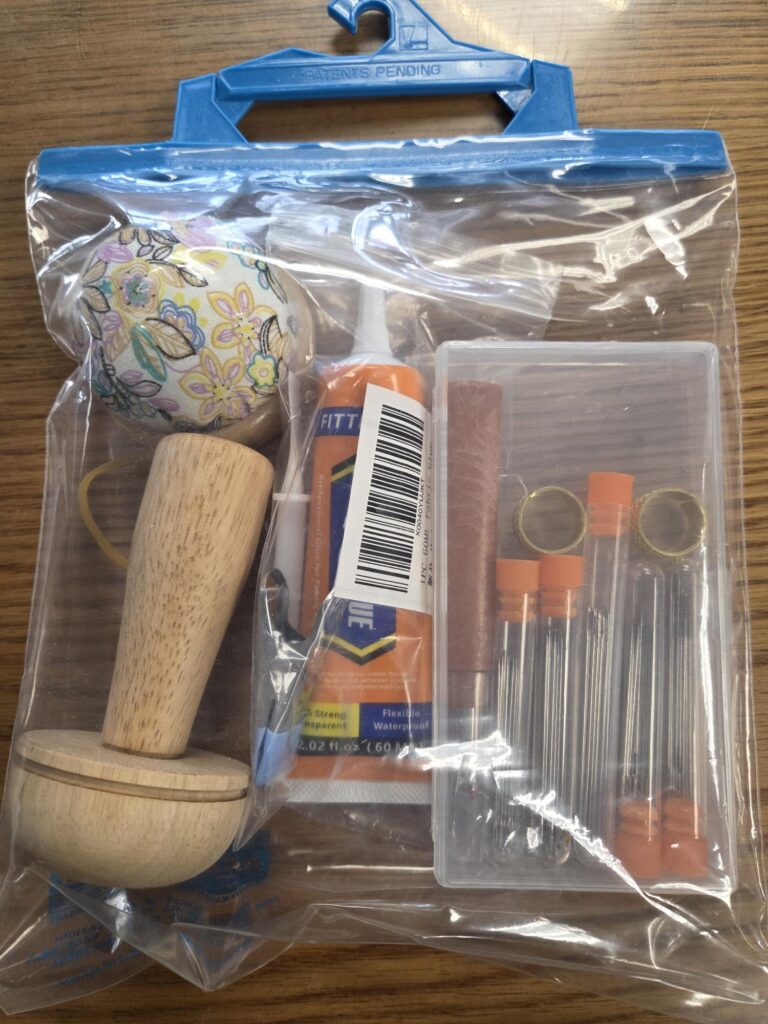 Image of plastic hanging bag containing 1 Wooden darning mushroom, 1 pin cushion, tube of needles, etc.