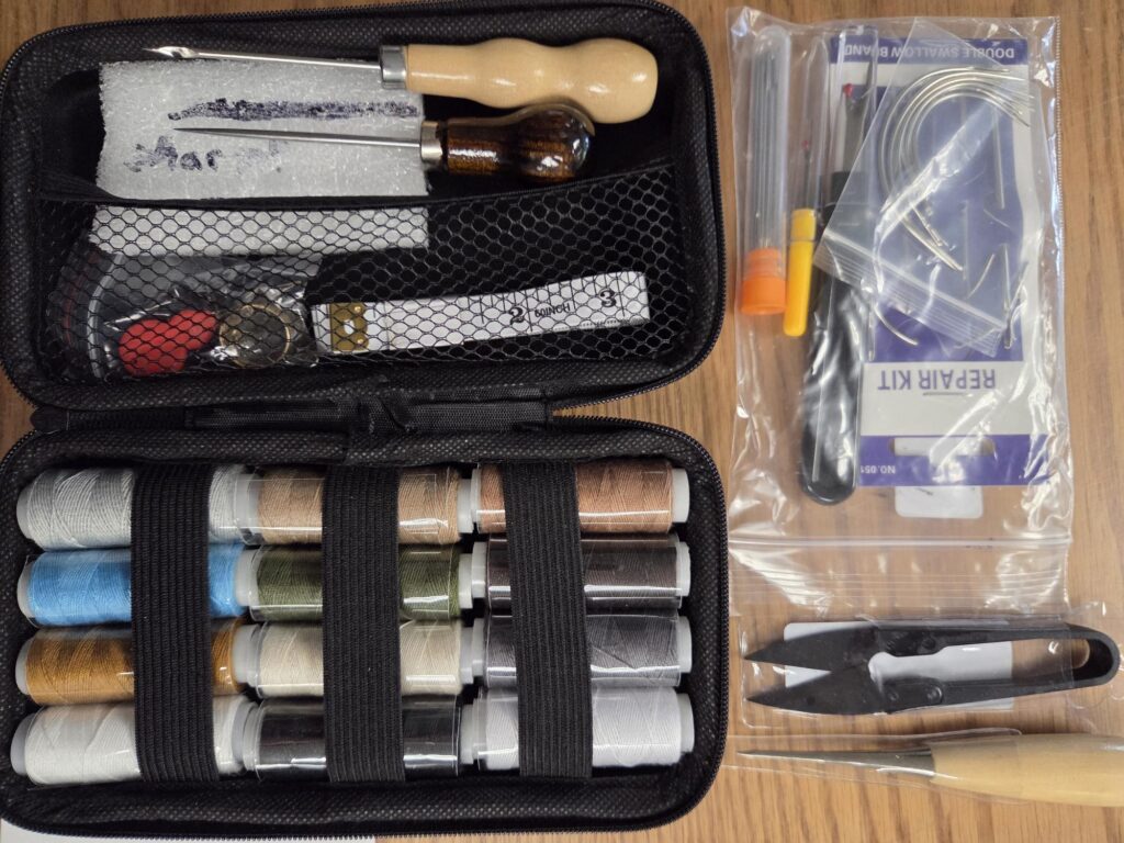 A hard zipper case (black) containing 12 spools heavy thread and various needles and tools.
