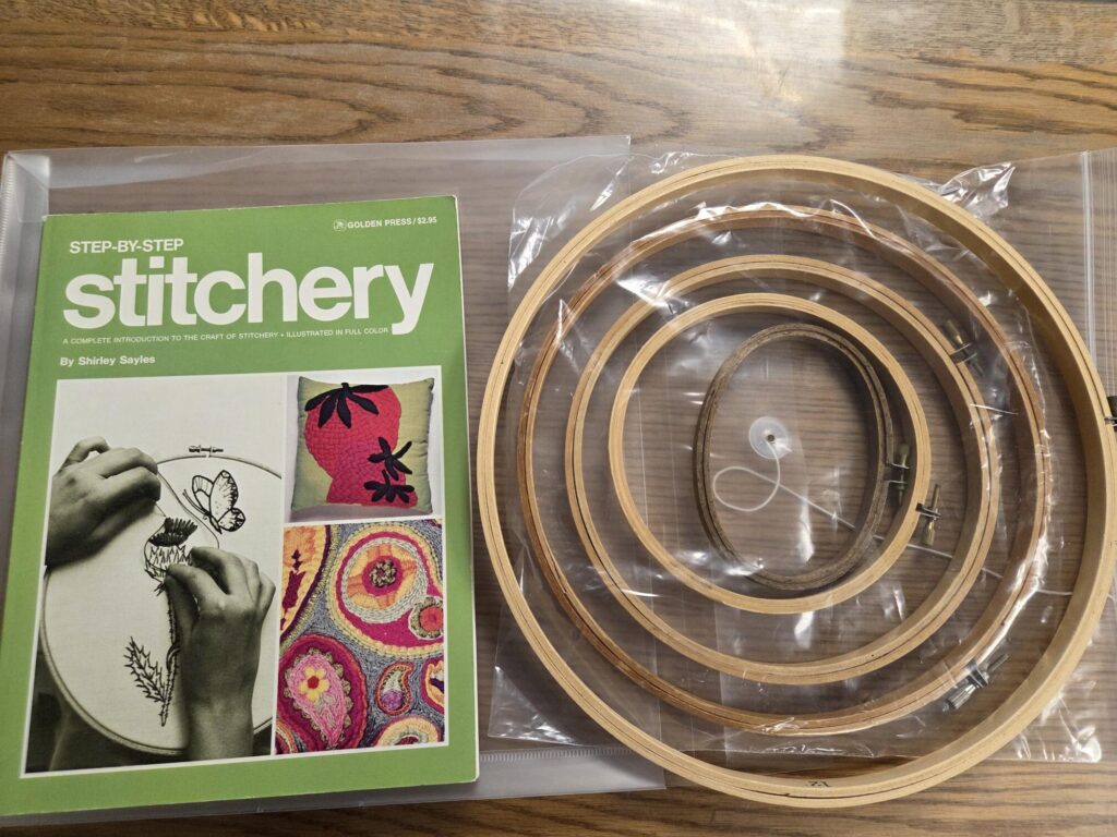 A book on Stitchery accompanied by wooden needlework hoops of various sizes, as a kit.